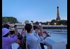A group of tourists on a Seine River Cruise taking photos of the Eiffel Tower 