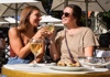 Two women sitting at a restaurant in Paris with wine and escargot.