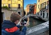 A boy taking a picture of Ponte Chiodo in Venice.