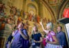 A group of tourists looking at the School of Athens with their guide from The Tour Guy.