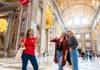 A pair of tourists inside of St. Peter's Basilica with their guide from The Tour Guy.