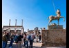 A group of tourists standing near a statue in Pompeii.
