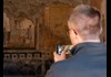 A man taking a photo of ancient frescoes on the walls of Pompeii.
