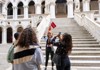 A woman taking a picture of the Doge's Palace with a tour group and guide from the Tour Guy.