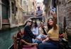 A group of tourists taking a selfie while on a Gondola ride in Venice.