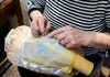 An older woman hand stitching lace designs.