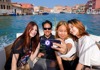 Tourists taking a selfie while on a boat in Venice.