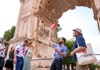 A group of tourists standing under the Arch of Titus in the Roman Forum.