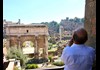 A man looking at the Arch of Titus in the Roman Forum.