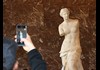 A tourist taking a picture of Venus di Milo in the Louvre Museum while on tour with The Tour Guy.