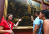 A couple taking a picture of Liberty Leading the People in the Louvre Museum with their guide from The Tour Guy.