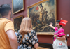 A couple of tourists in the Louvre standing in front of Liberty Leading the People while on tour with The Tour Guy.